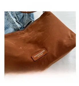Detail of brown suede tote bag featuring a leather fashion label and stitched accents
