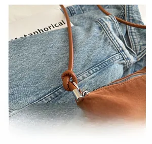 Close-up of brown suede tote bag featuring knot detail and silver metal hardware