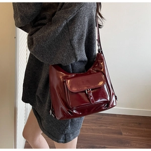 Détail du sac hobo en cuir verni bordeaux foncé avec poche à boucle vintage sur le devant