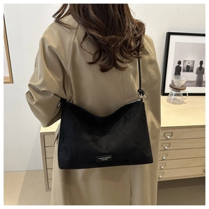 Lifestyle shot of a black minimalist crossbody bag with fashion letter metal logo detail