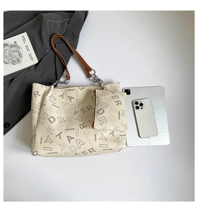 Close-up of creamy white tote bag set with lychee grain texture and metal chain detail