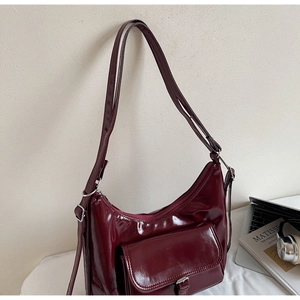 Détail macro du sac hobo vernis bordeaux avec poche avant et ferrures en argent poli