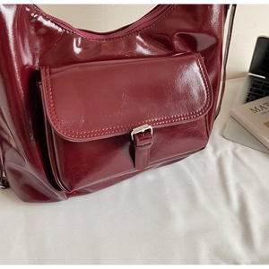 Détail du sac en cuir verni bordeaux brillant avec poche à boucle argentée
