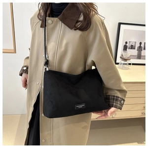 Detail of black crossbody bag in matte leather texture shown on model outfit