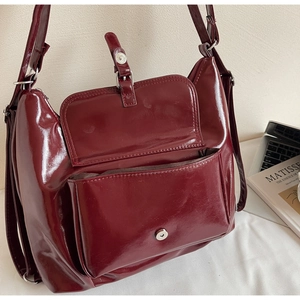 Détail du sac en cuir bordeaux brillant avec boucle argentée et poche à rabat