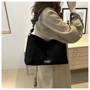 Detail of black large capacity shoulder bag with knotted strap and matte suede texture