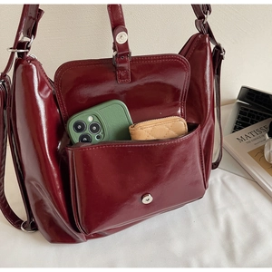 Détail du sac cabas en cuir verni bordeaux montrant l'intérieur spacieux et poches