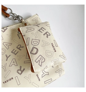 Close-up of beige tote and pouch set with monogram print and silver chain detail