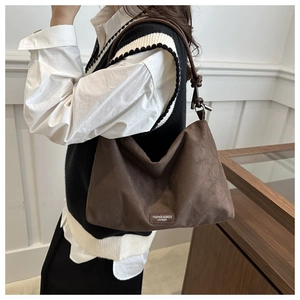 Detail of brown faux suede hobo bag featuring logo plate and textured strap