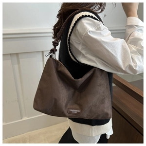 Detail of dark brown faux suede tote bag with leather logo patch and large capacity