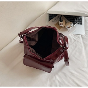 Détail du sac cabas en cuir verni bordeaux montrant l'intérieur zippé et les boucles