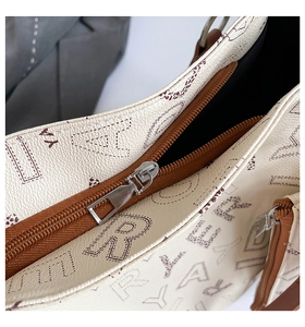 Detail of lychee textured leather tote bag with silver metal zipper and letter prints