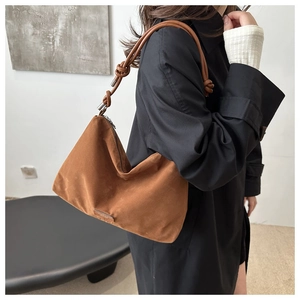Detail of caramel brown moon bag with thick knotted shoulder strap and silver hardware