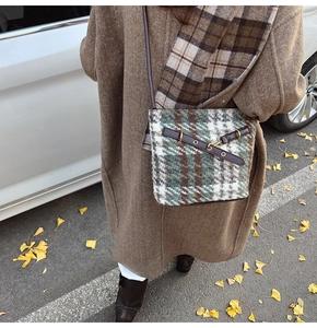 Détail du sac seau à carreaux verts avec lanières en cuir marron et boucles en métal