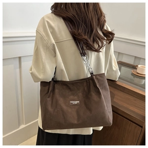 Dettaglio borsa tote in pelle scamosciata marrone scuro con catena d'argento e placca