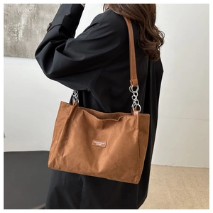 Dettaglio borsa tote in pelle scamosciata caramello con catena in metallo e cuoio