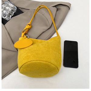 Vista dall'alto di una borsa a secchiello giallo acceso in pelle scamosciata e smartphone