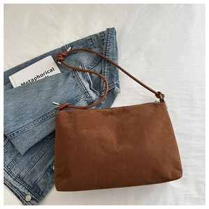 Close-up of caramel suede crossbody bag with knotted rope strap on a lifestyle setting