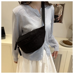 Detail of black corduroy crossbody bag with adjustable strap and textured fabric