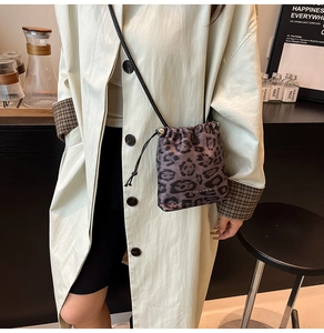 Sac à bandoulière léopard avec cordon de serrage porté par un mannequin en trench-coat