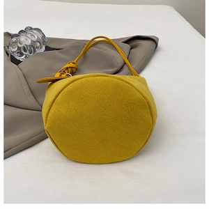 Vista dettagliata della borsa a secchiello scamosciata giallo zenzero con manico in pelle annodato