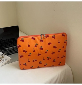Detail of orange laptop sleeve with red cherry prints and dual metal zippers