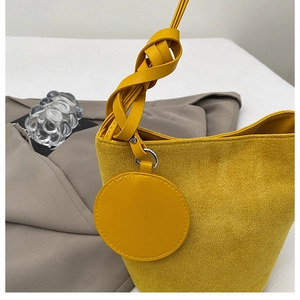 Dettaglio della borsa a secchiello in camoscio giallo con manico intrecciato decorativo