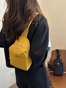 Bright yellow nylon crossbody bag for women with natural texture and round metal logo detail