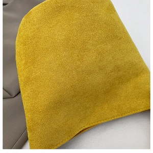 Dettaglio della borsa a secchiello in camoscio giallo zenzero con cuciture e finitura opaca