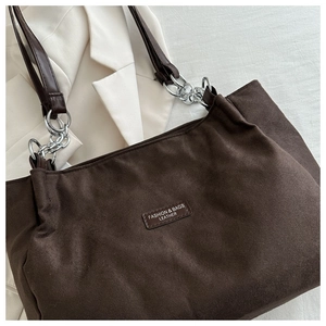 Dettaglio della borsa tote in pelle scamosciata marrone scuro con tracolla in pelle e catena