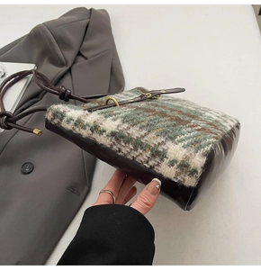 Vue détaillée du contraste entre le tissu en tweed et le cuir marron sur le sac seau