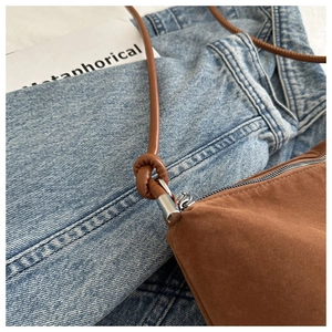 Detail of brown suede shoulder bag featuring a knotted leather strap and silver metal ring