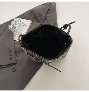 Détail d'un sac seau en tweed avec bordure en cuir montrant la poche zippée intérieure