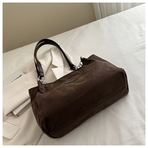 Dettaglio della borsa tote in pelle scamosciata marrone con catene argentate e texture
