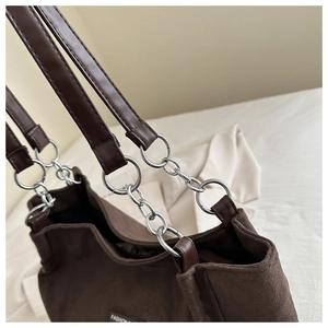 Dettaglio della borsa tote in pelle scamosciata marrone con catena d'argento e logo