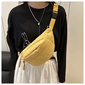 Primer plano de la textura de pana amarillo jengibre y correa ajustable del bolso