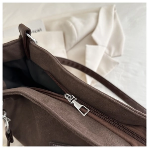 Dettaglio della borsa tote in pelle scamosciata marrone scuro con cerniera in metallo