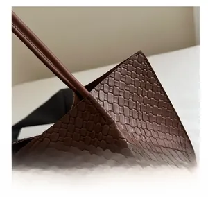 Close-up of brown woven tote bag showing intricate leather texture and precise stitching
