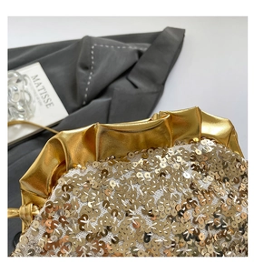 Dettaglio di paillettes dorate e bordo in pelle metallizzata a pieghe di borsa da sera