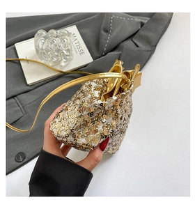Dettaglio di una mini borsa a mano con paillettes dorate e tracolla sottile