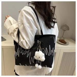 Dettaglio borsa shopper nera con ricami a onde e ciondolo in peluche a forma di nuvola