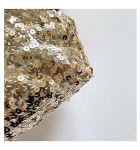 Vista macro dei lustrini dorati scintillanti cuciti sulla rete bianca della borsa di lusso