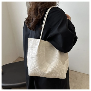 Detailed view of the woven texture and cream leather on a large shoulder tote bag