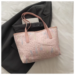 Vista dettagliata della borsa tote rosa con design goffrato e ricami colorati di qualità