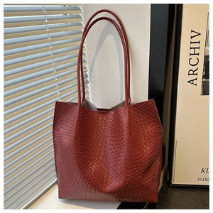 Detailed view of large reddish brown tote bag featuring unique woven faux leather texture