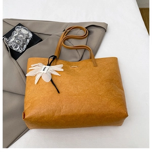 Detailed top view of a large ginger tote bag with unique pleat texture and floral charm