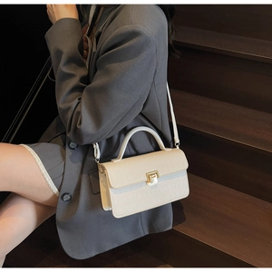 Detail of white crocodile texture handbag with gold buckle on wooden stairs