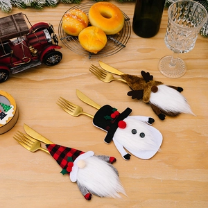 Three Christmas gnome cutlery holders on a wooden table with gold knives and forks
