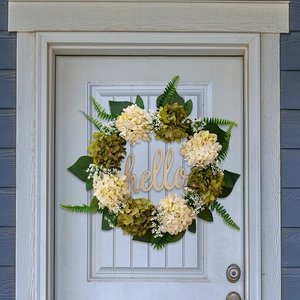 Detail of faux hydrangea wreath with fern leaves and wooden hello sign on a front door