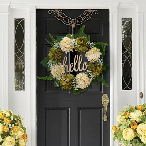 Close-up of artificial hydrangea wreath with green leaves and a wooden hello sign on a door